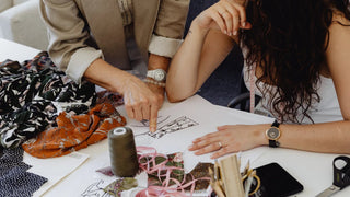 Photo of women designers looking a fashion sketch drawing with fabrics and threads on the side